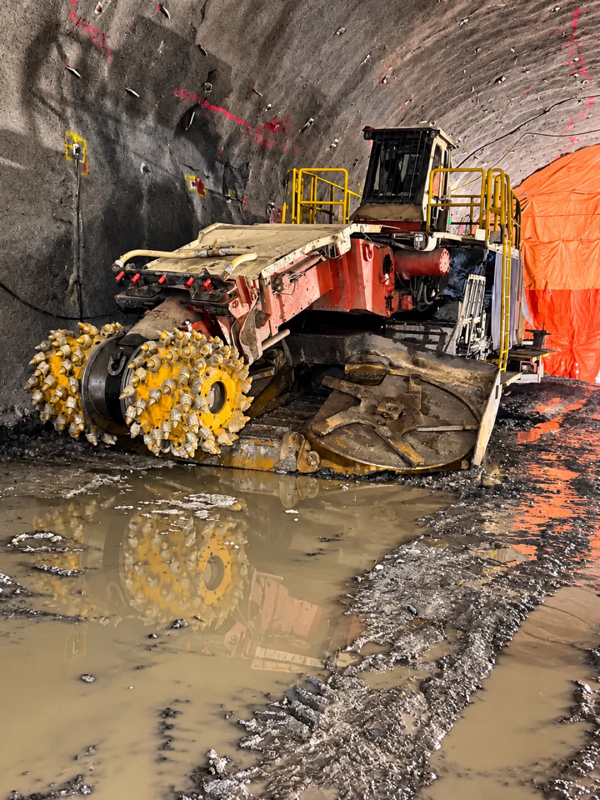 Machine de creusage à tambours dans un tunnel, son reflet dans l’eau au sol
