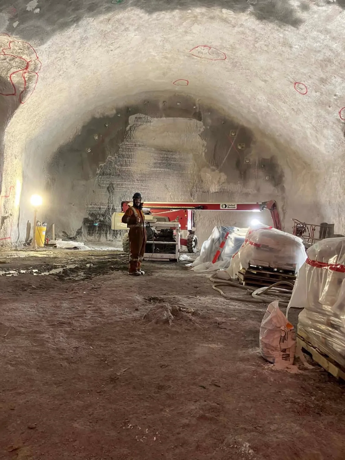 Un mécanicien en équipement orange dans un tunnel en béton projeté